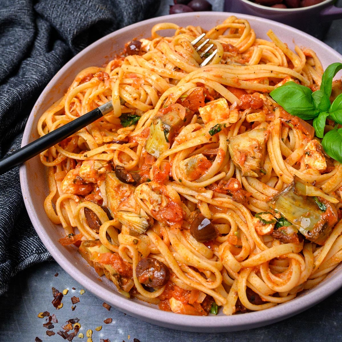 Spaghetti noodles with chicken, olive slices and basil. 
            Image found on https://skinnyspatula.com/mediterranean-pasta/