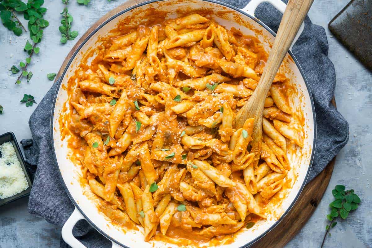 Penne pasta with orange sauce and bits of greens and cheese sprinkled on top. 
                    Image found on https://bakingmischief.com/penne-alla-vodka-with-chicken/